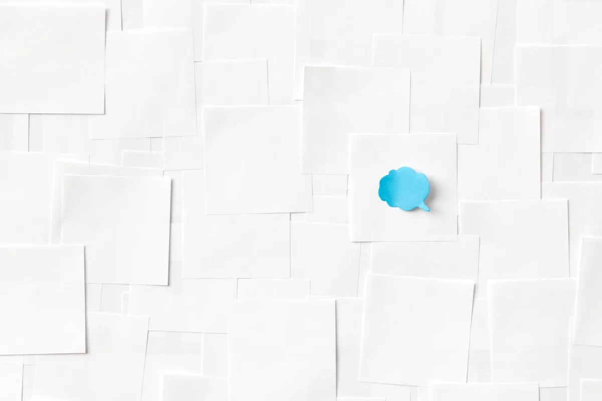A blue speech bubble on a white paper surface symbolizing communication and ideas. A blue speech bubble on a white paper surface symbolizing communication and ideas.