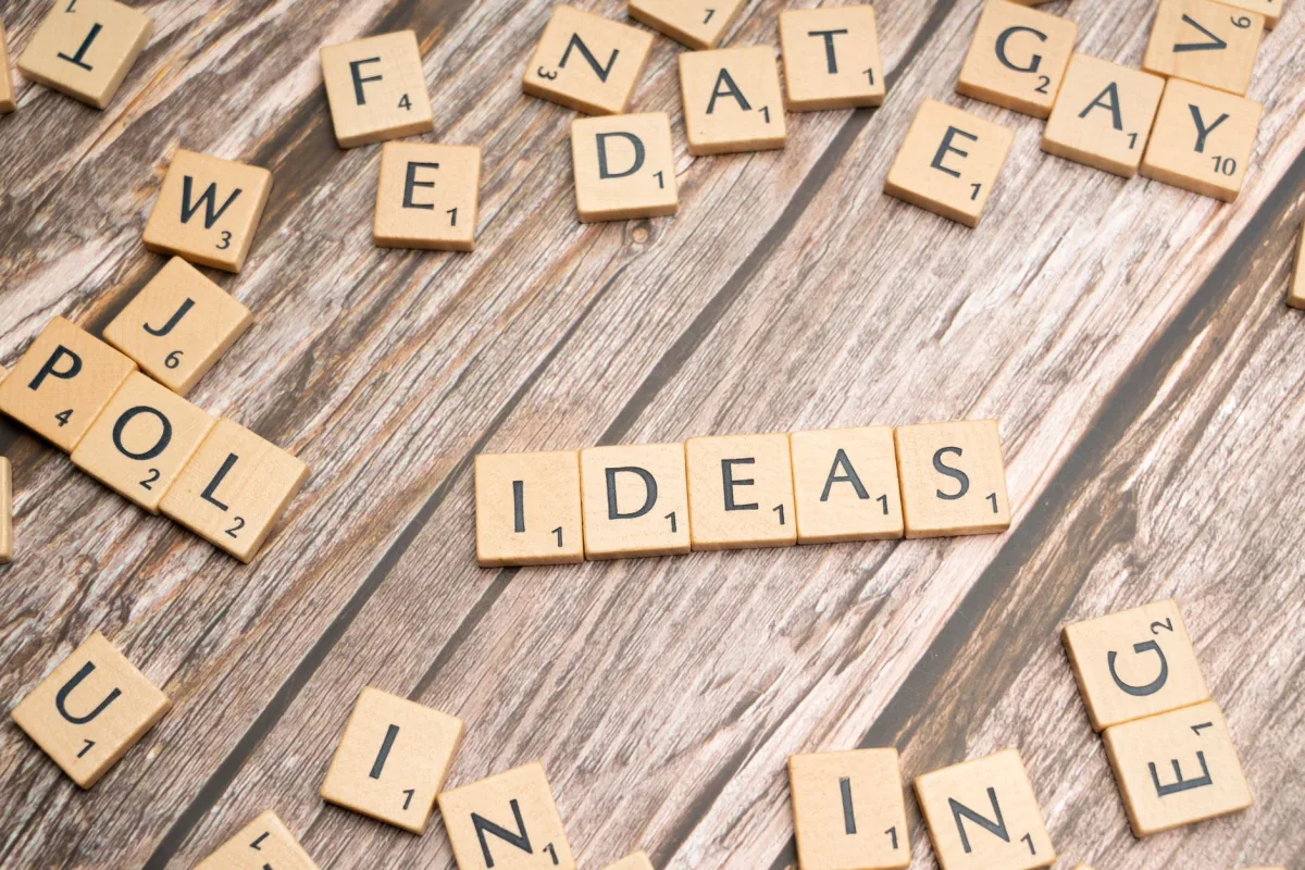 Scrabble word tiles forming 'IDEAS' on a wooden texture background, symbolizing creativity.