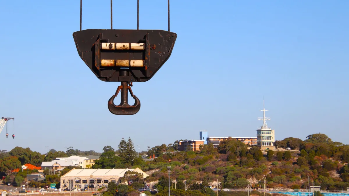 Close-up of a crane hook with a cityscape background, showcasing urban industrial themes. Close-up of a crane hook with a cityscape background, showcasing urban industrial themes.