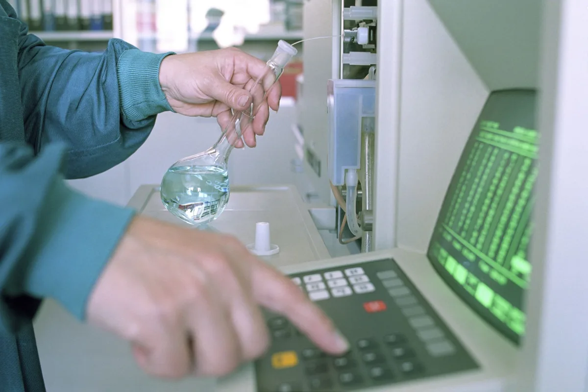 Close-up of a scientist operating lab equipment a flask in hand.