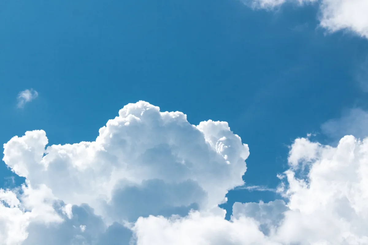 An expansive view of fluffy white clouds set against a clear blue sky, capturing a peaceful nature scene.
