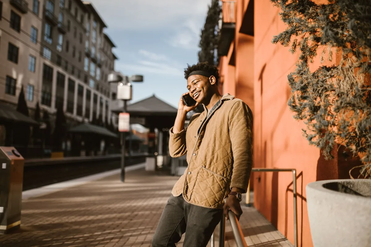 Smiling young man in a city setting talking on his phone outdoors. Smiling young man in a city setting talking on his phone outdoors.