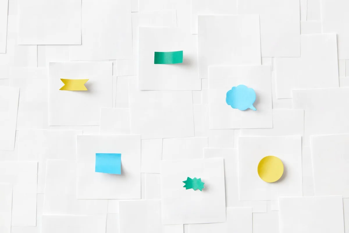 An arrangement of colorful sticky notes placed on a background of white papers. An arrangement of colorful sticky notes placed on a background of white papers.