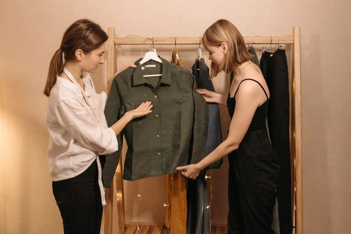 Two women discussing a green shirt in a professional tailor's workspace. Two women discussing a green shirt in a professional tailor's workspace.