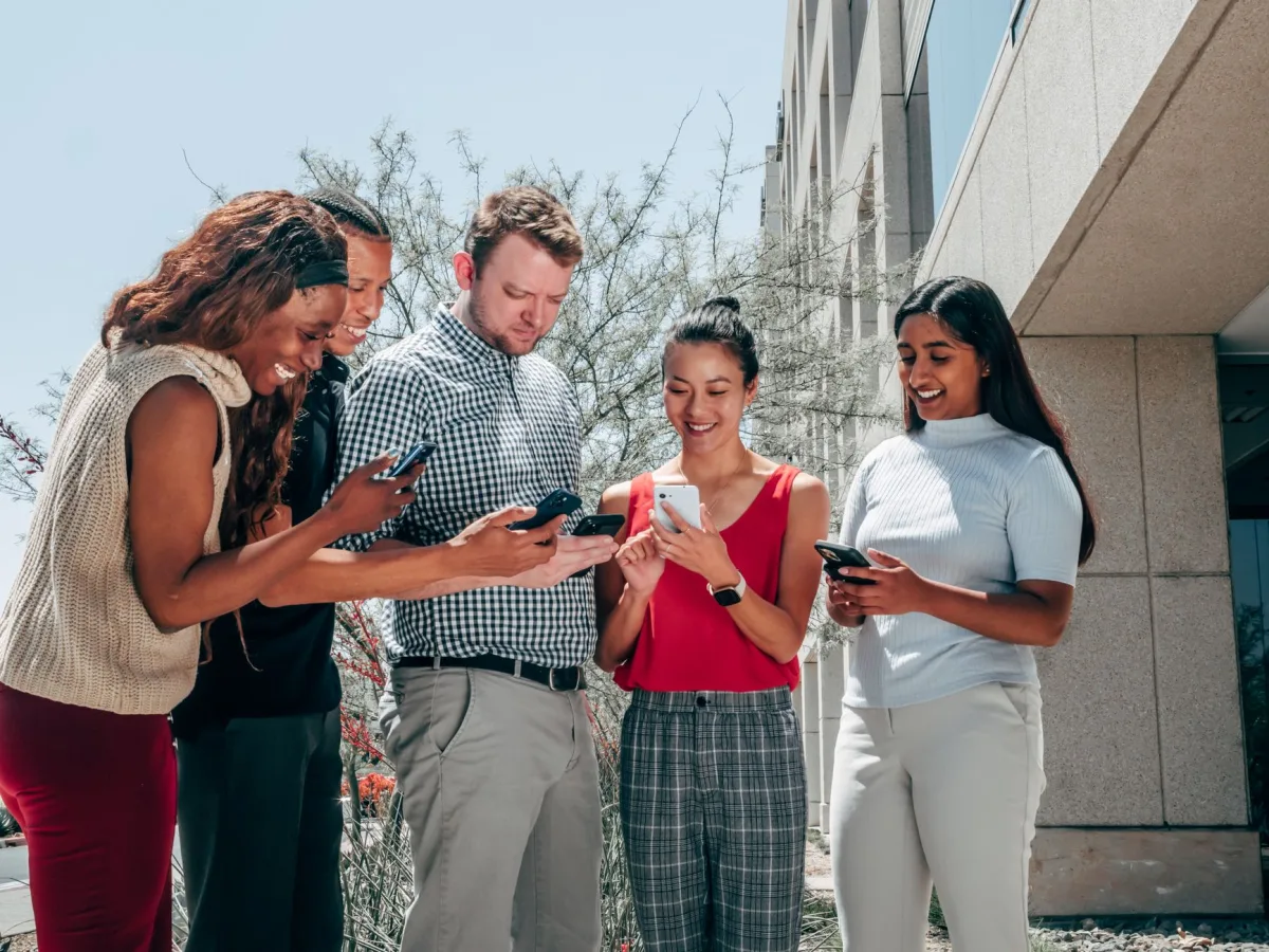Five adults socializing with smartphones, representing technology and diversity.