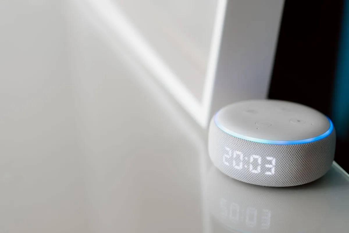 Close-up of a speaker with a digital clock display on a minimalist surface.