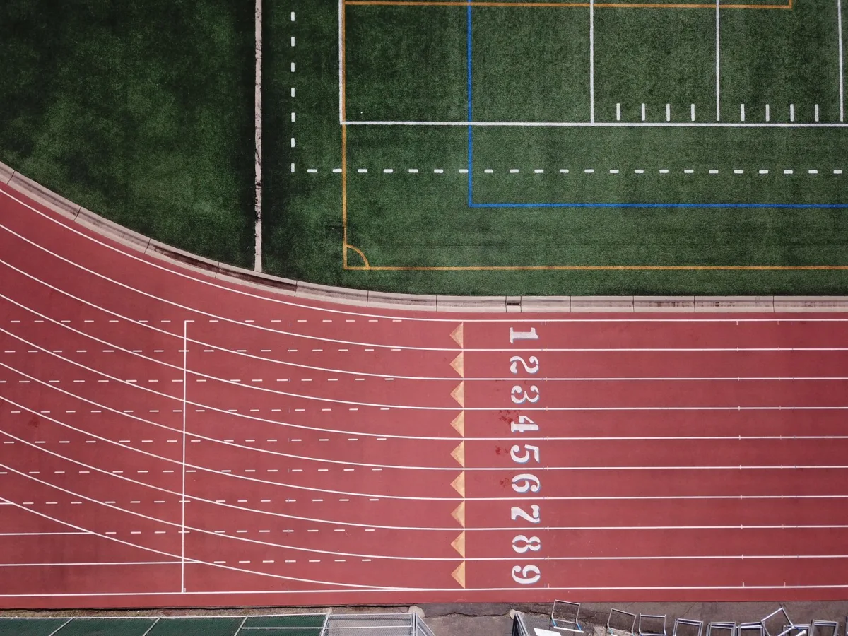 Aerial perspective of a red running track and adjacent green field. Aerial perspective of a red running track and adjacent green field.