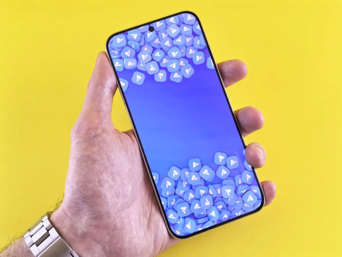 Smartphone displaying social media icons, held in a hand against a bright yellow background. Smartphone displaying social media icons, held in a hand against a bright yellow background.