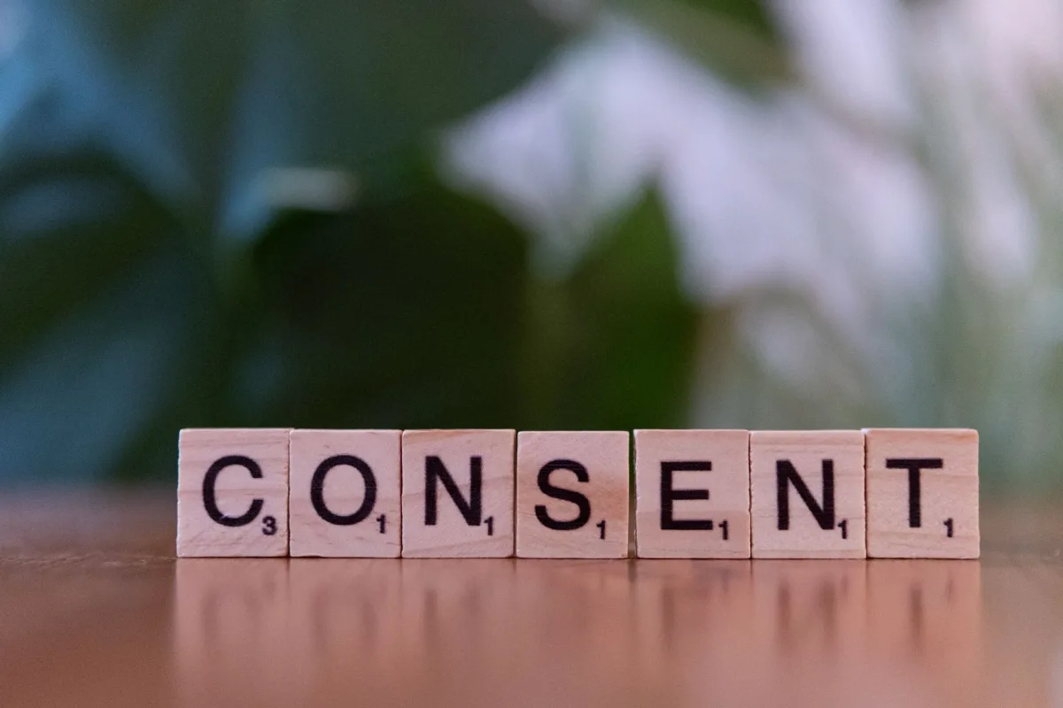 Close-up Scrabble tiles spelling 'Consent' on a wooden surface, focusing on and Close-up Scrabble tiles spelling 'Consent' on a wooden surface, focusing on and