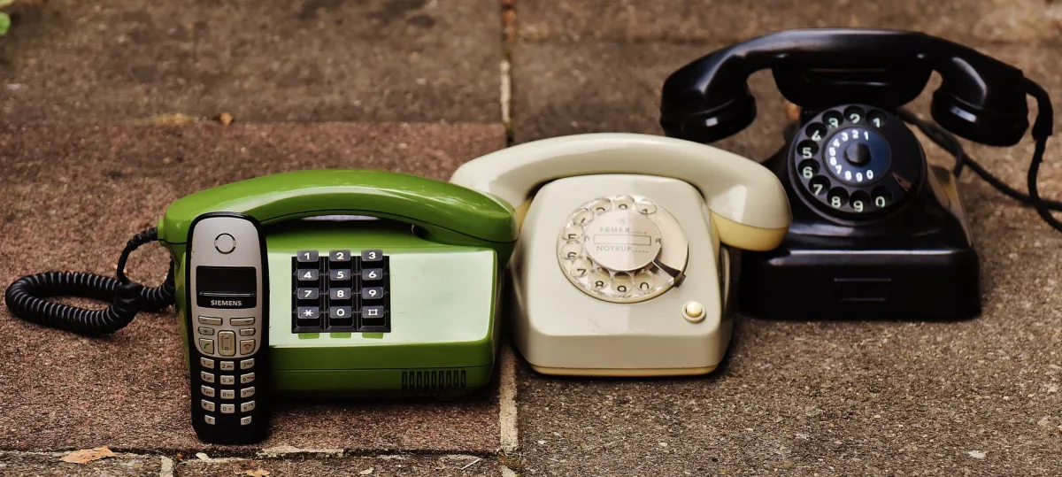A variety antique, vintage, and modern telephones displayed on pavement. A variety antique, vintage, and modern telephones displayed on pavement.