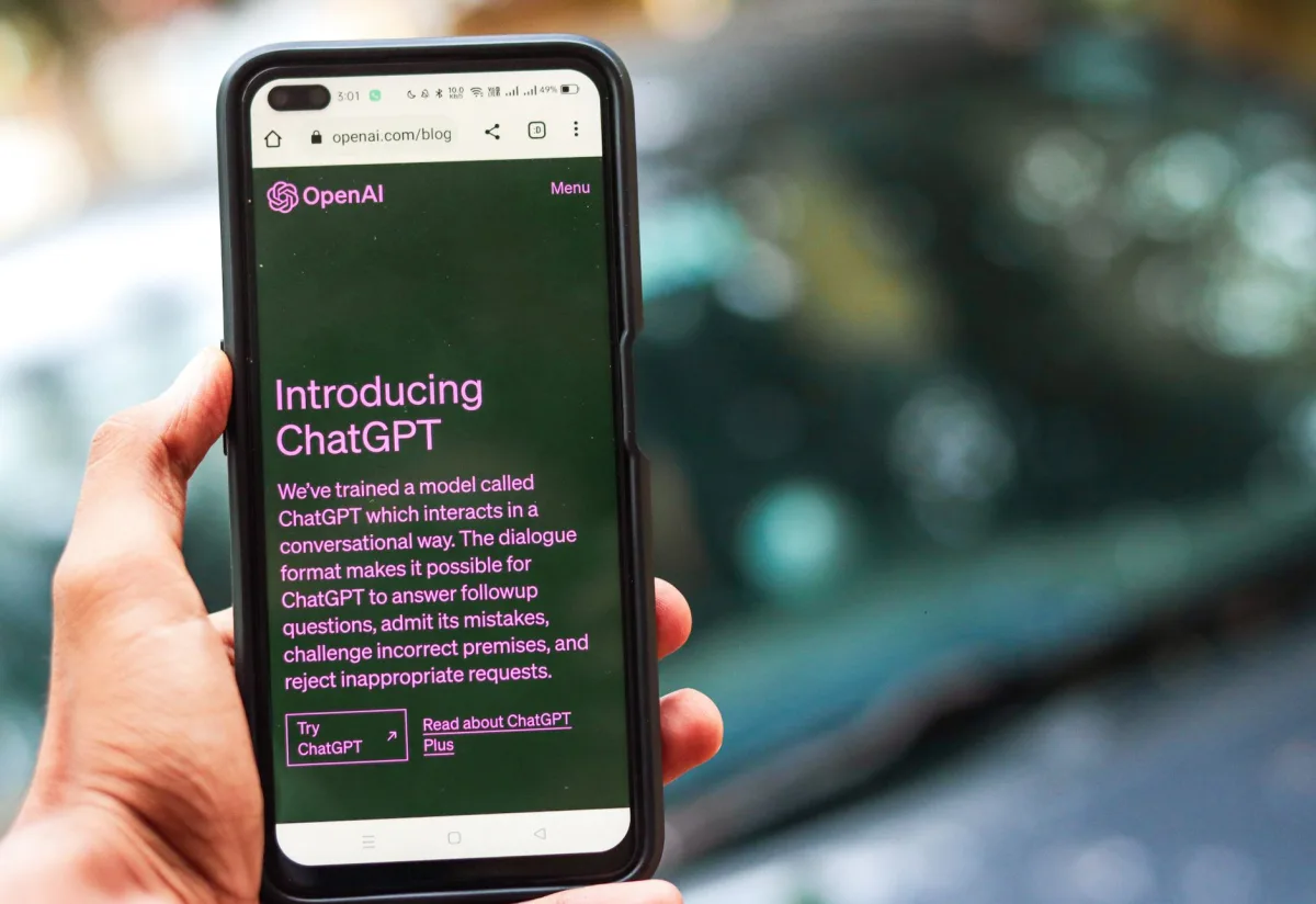 Close-up a smartphone showing ChatGPT details on OpenAI website, held by a person.