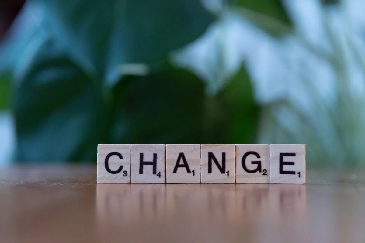 Scrabble tiles spelling 'CHANGE' on a wooden surface with a blurred green background. Scrabble tiles spelling 'CHANGE' on a wooden surface with a blurred green background.