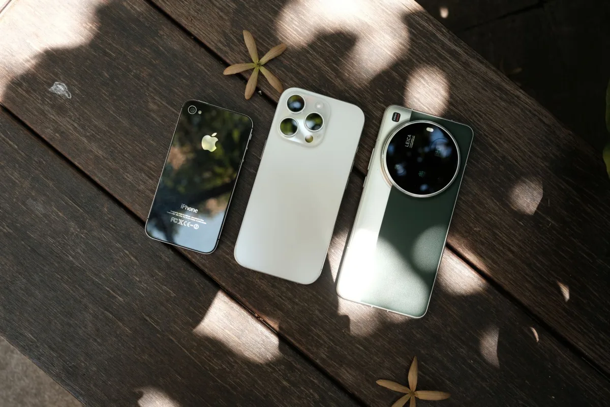 Three modern smartphones displayed on a wooden surface with natural lighting. Three modern smartphones displayed on a wooden surface with natural lighting.