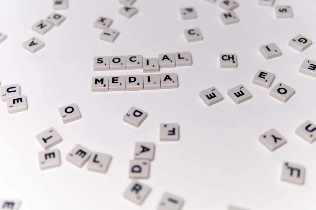 White Scrabble tiles forming phrase 'social media' on a scattered background.