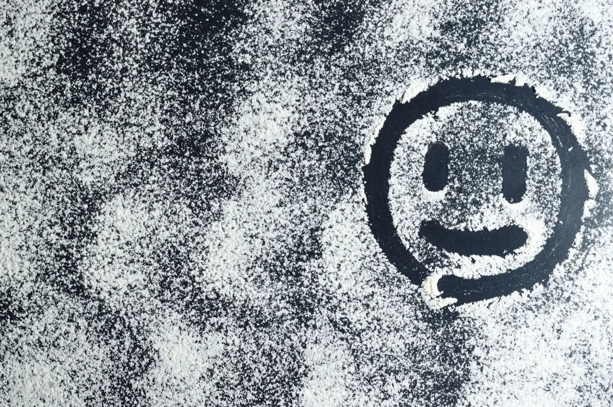 Artistic smiley face drawn through white powder on a black surface, creating an abstract texture. Artistic smiley face drawn through white powder on a black surface, creating an abstract texture.