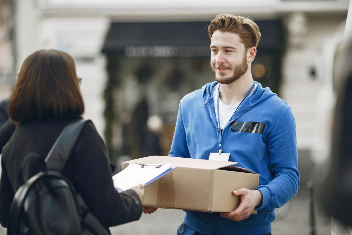 Friendly delivery person in blue hoodie gives package to outside. Perfect for business images. Friendly delivery person in blue hoodie gives package to outside. Perfect for business images.