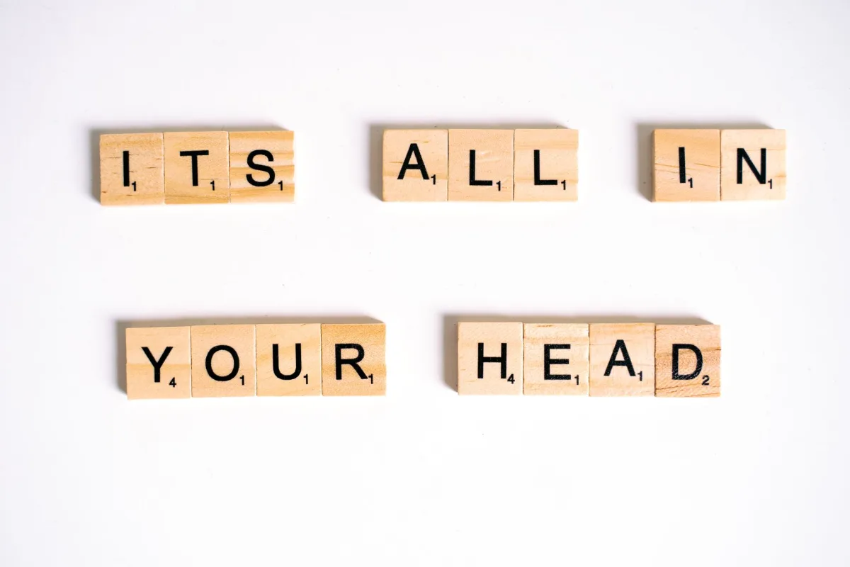 Wooden Scrabble tiles arranged to spell 'ITS ALL IN YOUR HEAD' on a white background. Wooden Scrabble tiles arranged to spell 'ITS ALL IN YOUR HEAD' on a white background.