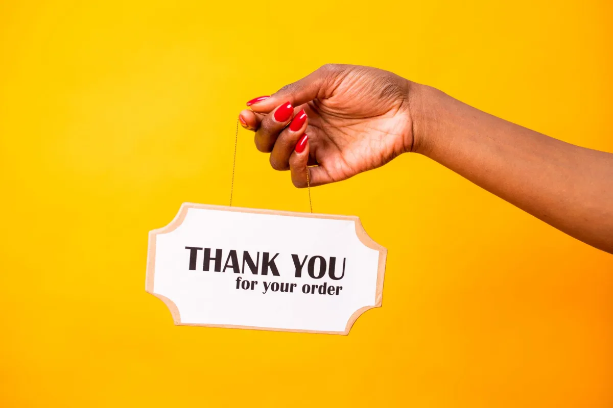 A hand holding a sign on a bright yellow background, expressing gratitude. A hand holding a sign on a bright yellow background, expressing gratitude.