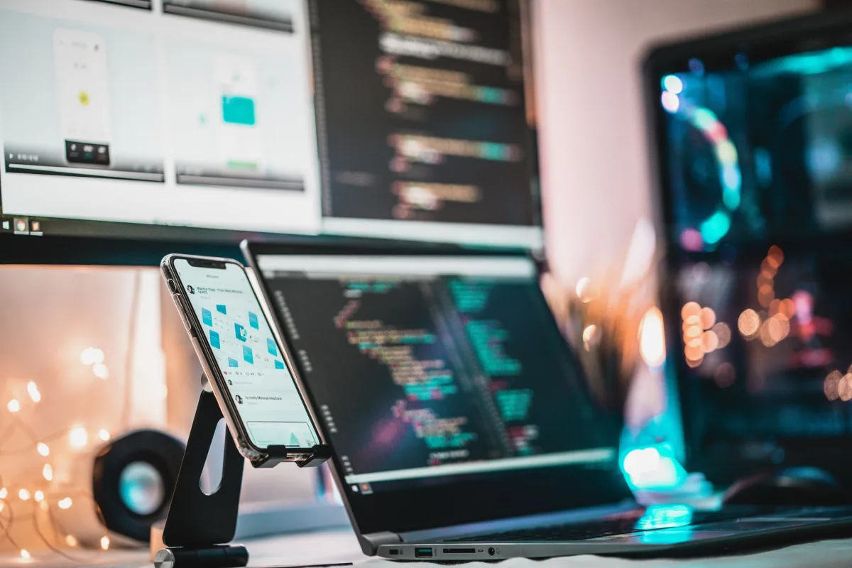 A close-up view of a tech setup with gadgets, coding screen, and smartphone, perfect for tech themes. A close-up view of a tech setup with gadgets, coding screen, and smartphone, perfect for tech themes.