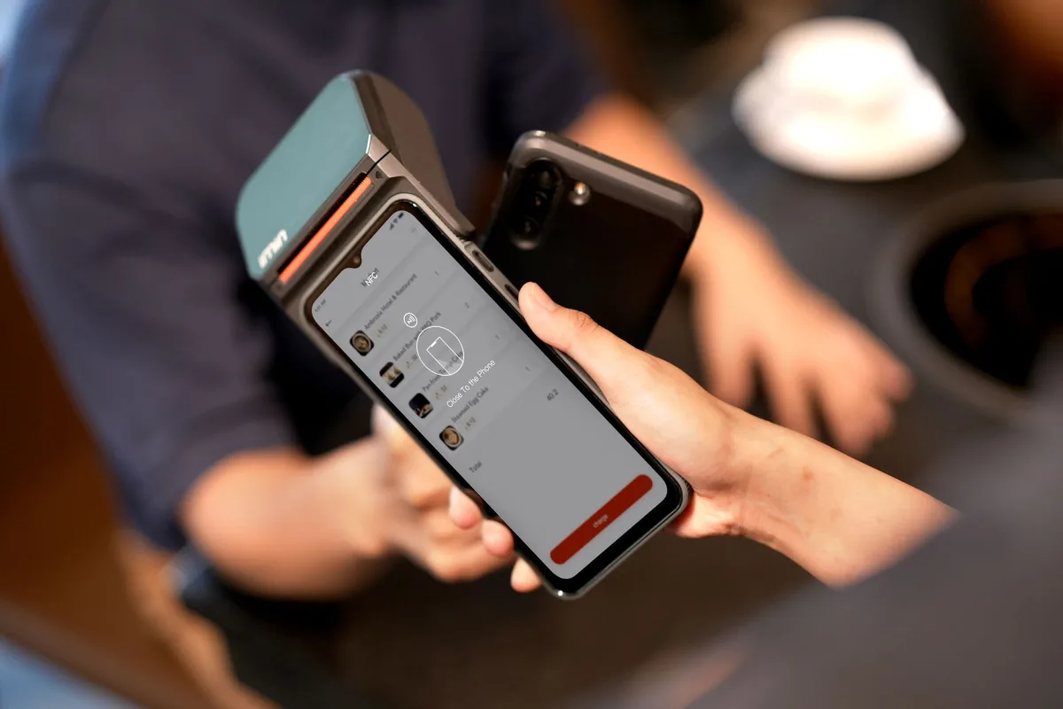 Close-up a smartphone making a contactless payment at a modern payment terminal in a retail environment.