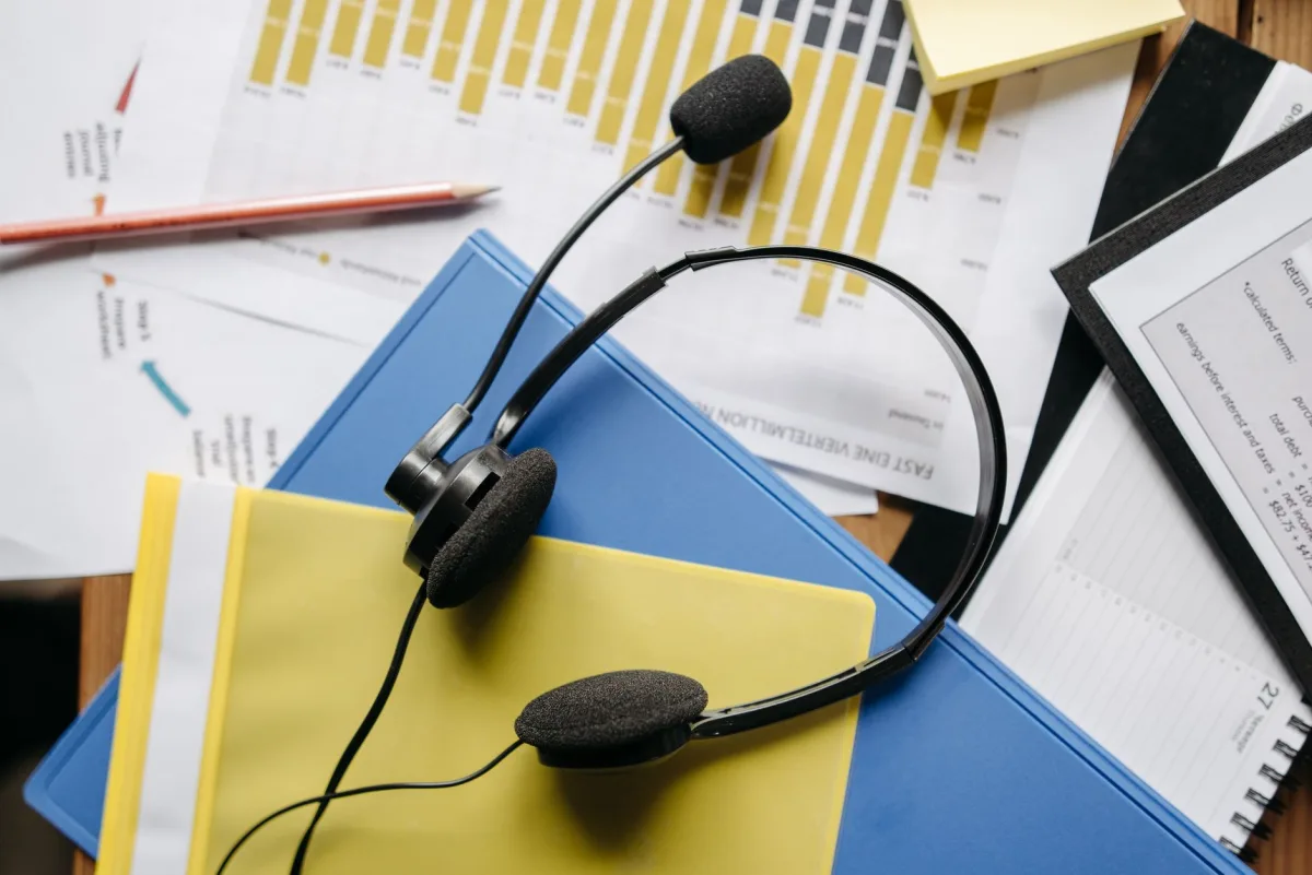 Close-up of an office desk with headset, charts, and documents showcasing customer service Close-up of an office desk with headset, charts, and documents showcasing customer service