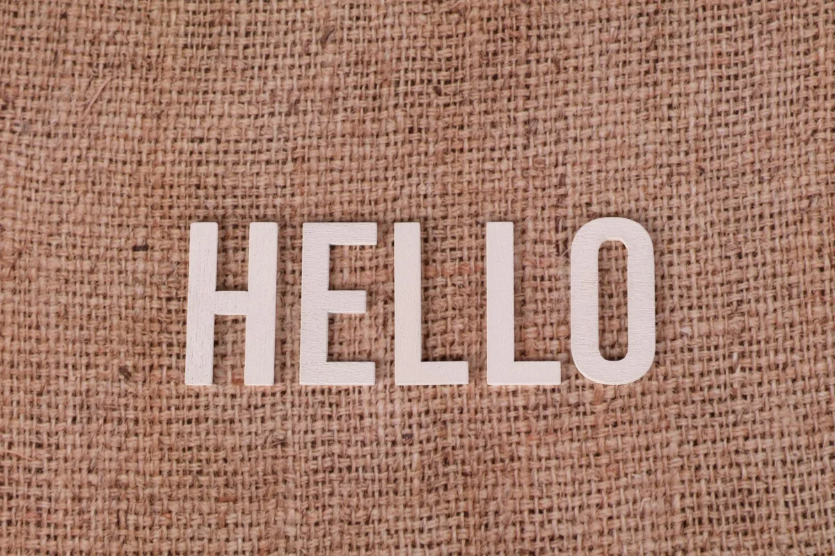 Wooden letters form the word 'HELLO' on a rustic burlap background, offering warm greetings.