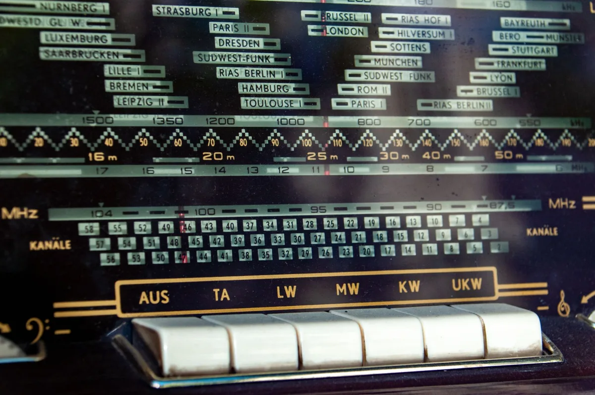 Close-up of a vintage radio dial displaying bands station names.