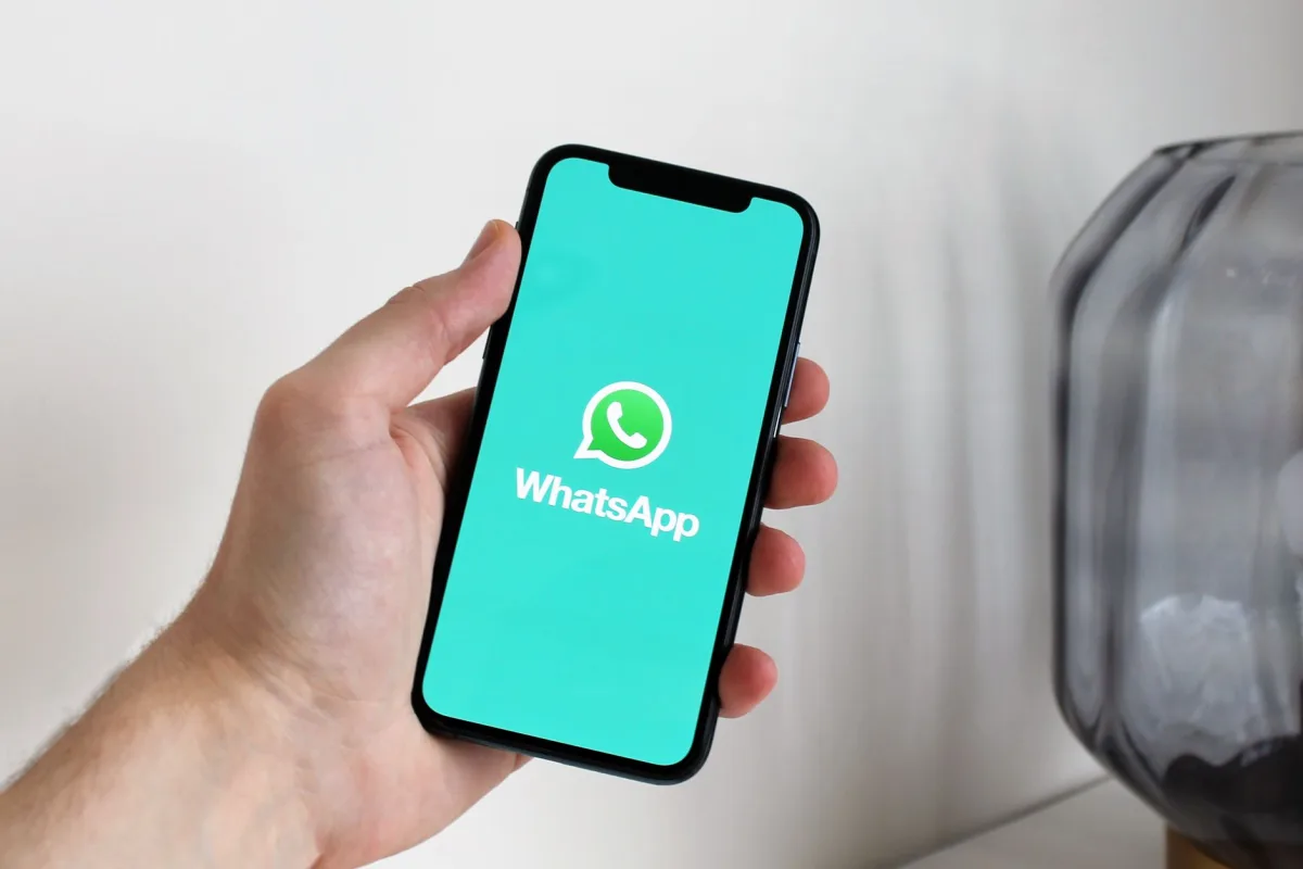 Close-up of a hand holding a smartphone displaying the WhatsApp app screen. Close-up of a hand holding a smartphone displaying the WhatsApp app screen.