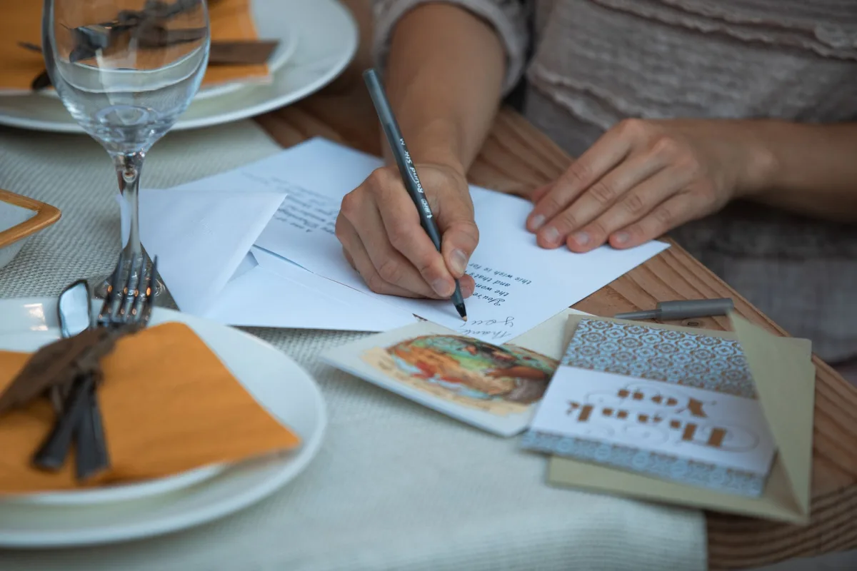 Woman writing notes at a Thanksgiving dinner table setting.