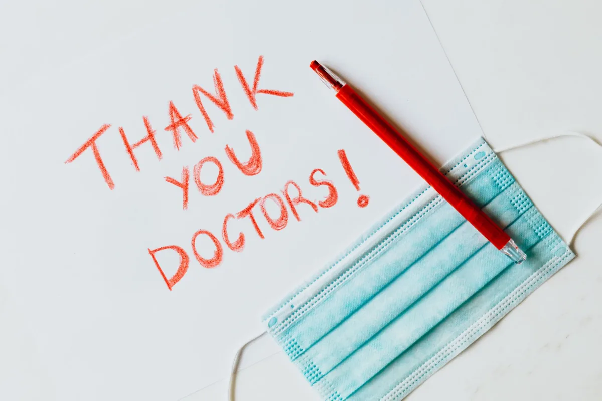Red handwritten note with a face mask and pen, showing appreciation for doctors.