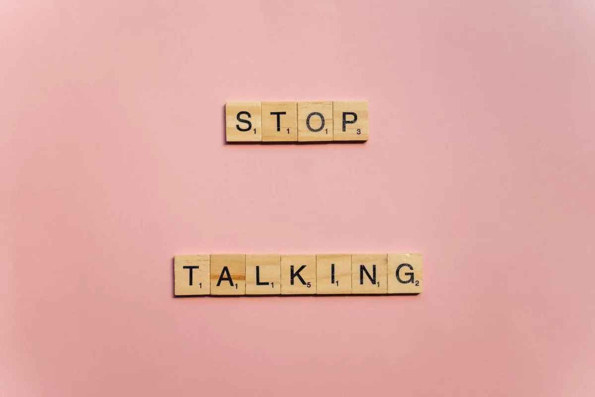 Wooden Scrabble tiles on pink background spelling 'Stop Talking'. Wooden Scrabble tiles on pink background spelling 'Stop Talking'.