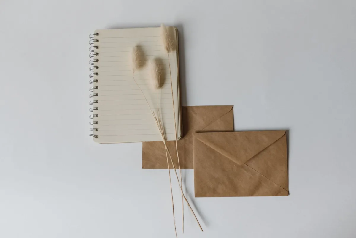Simple flat lay of a notebook with brown envelopes on a neutral background. Ideal for creative projects. Simple flat lay of a notebook with brown envelopes on a neutral background. Ideal for creative projects.