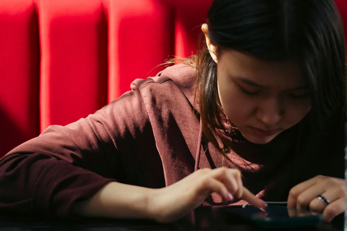 Young woman focused on her smartphone with a bright red background, representing modern technology lifestyle. Young woman focused on her smartphone with a bright red background, representing modern technology lifestyle.