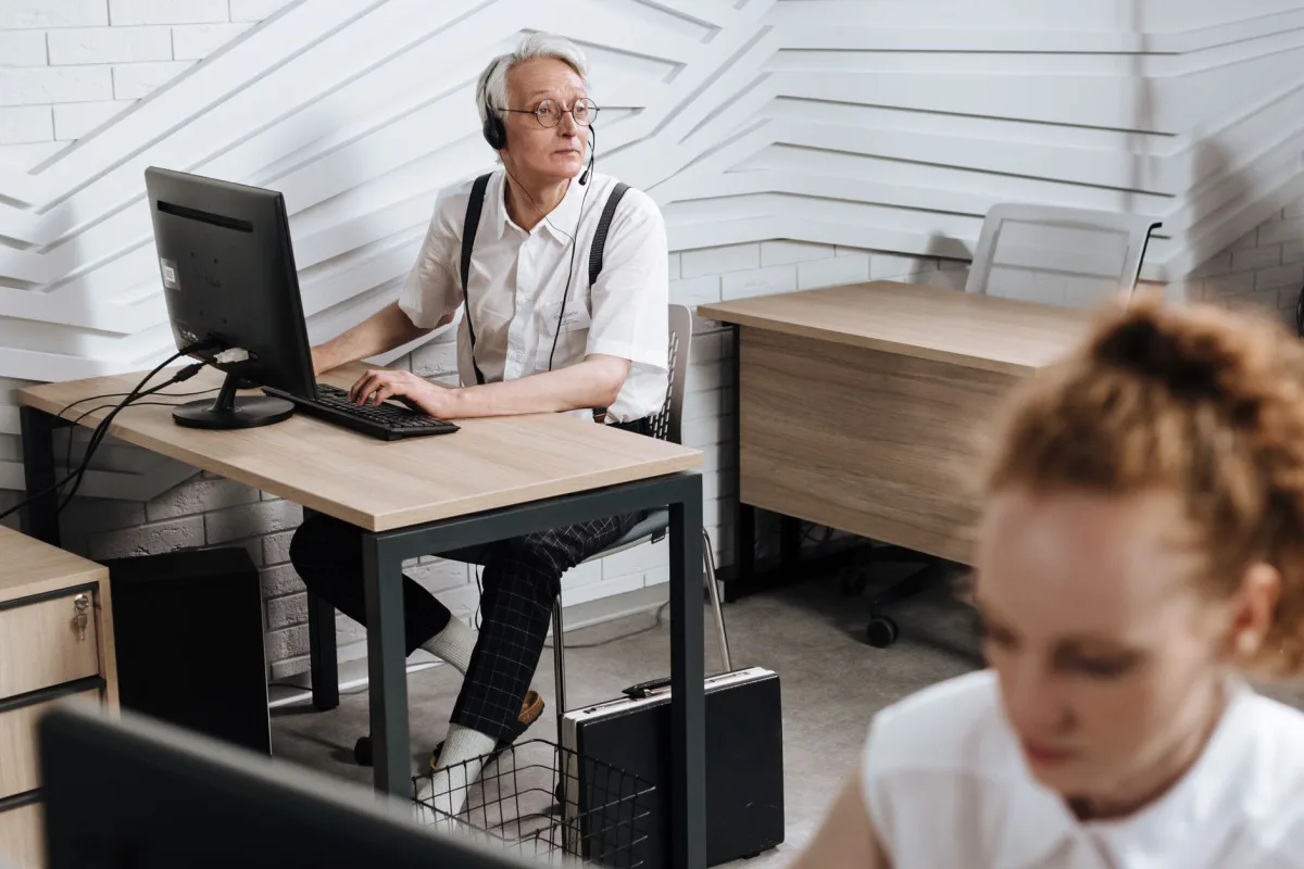 Senior call center agent a headset and computer in a modern office setting. Senior call center agent a headset and computer in a modern office setting.