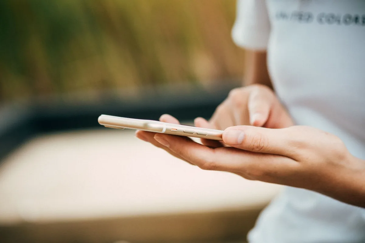 Close-up of a person a smartphone outdoors, focusing on hands and device. Close-up of a person a smartphone outdoors, focusing on hands and device.