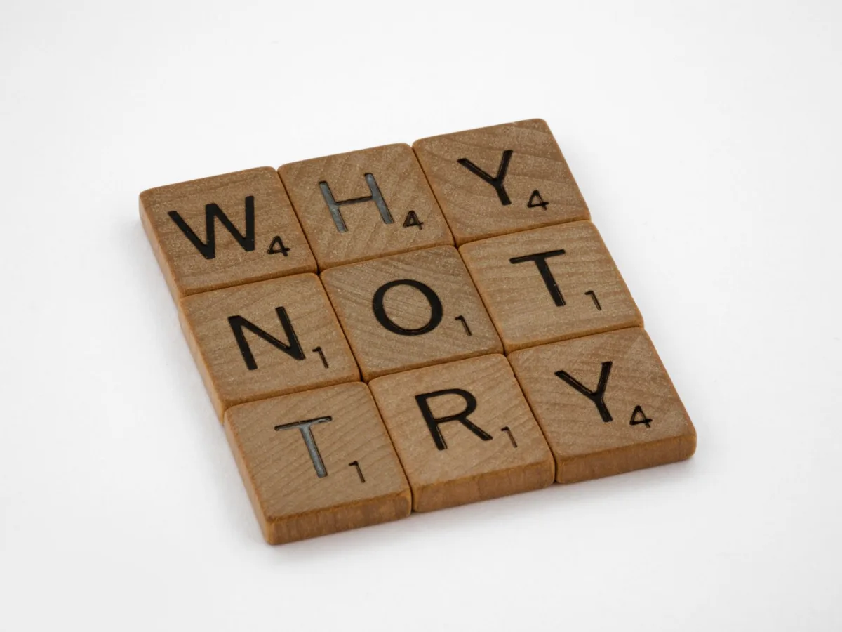 Wooden Scrabble tiles on a white background spelling the phrase 'Why Not Try'. Wooden Scrabble tiles on a white background spelling the phrase 'Why Not Try'.