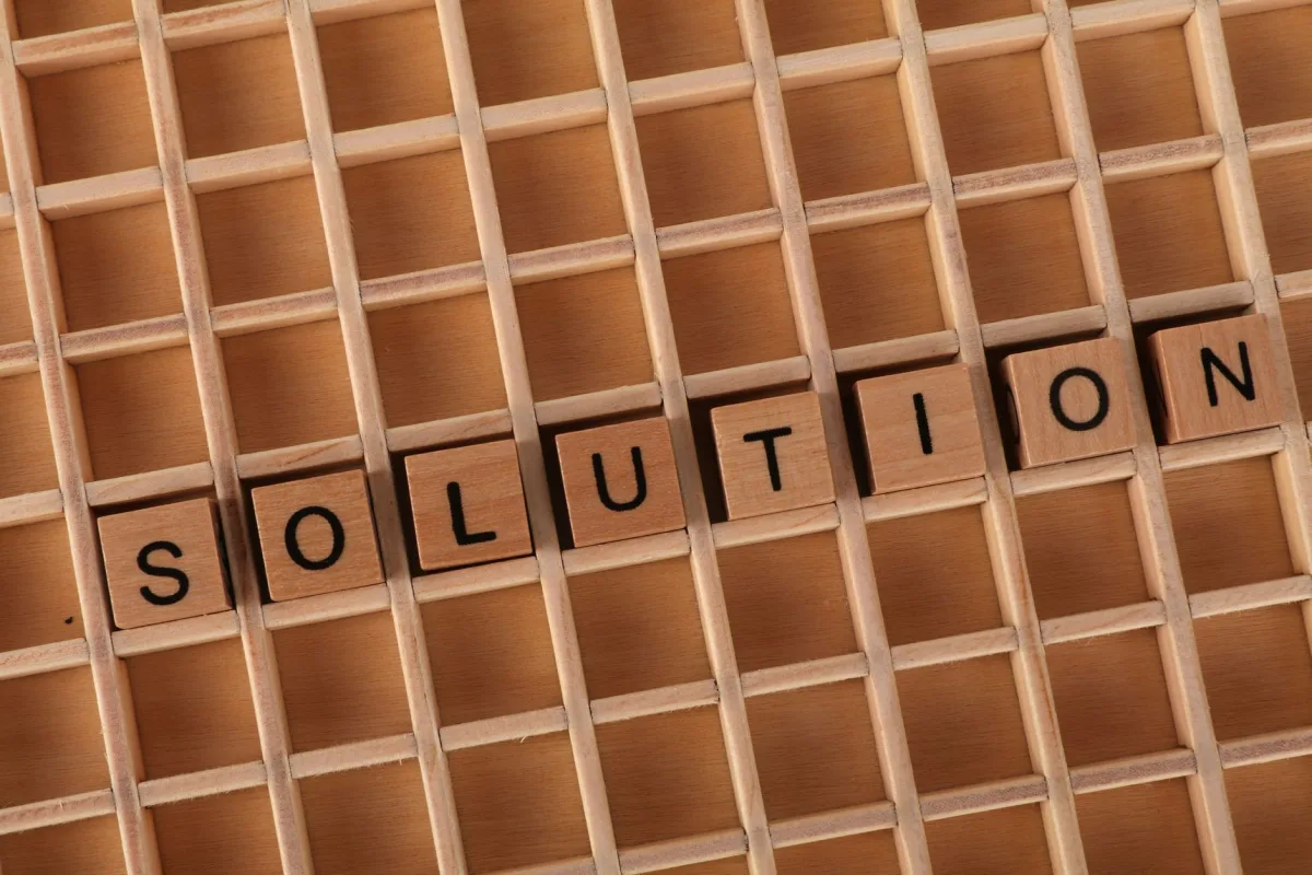 Word tiles spelling 'solution' on a wooden grid background for business concept. Word tiles spelling 'solution' on a wooden grid background for business concept.