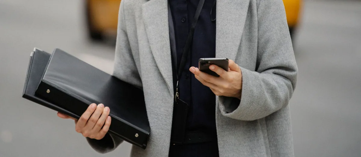 Crop anonymous well dressed female executive with folders text on cellphone on urban road Crop anonymous well dressed female executive with folders text on cellphone on urban road