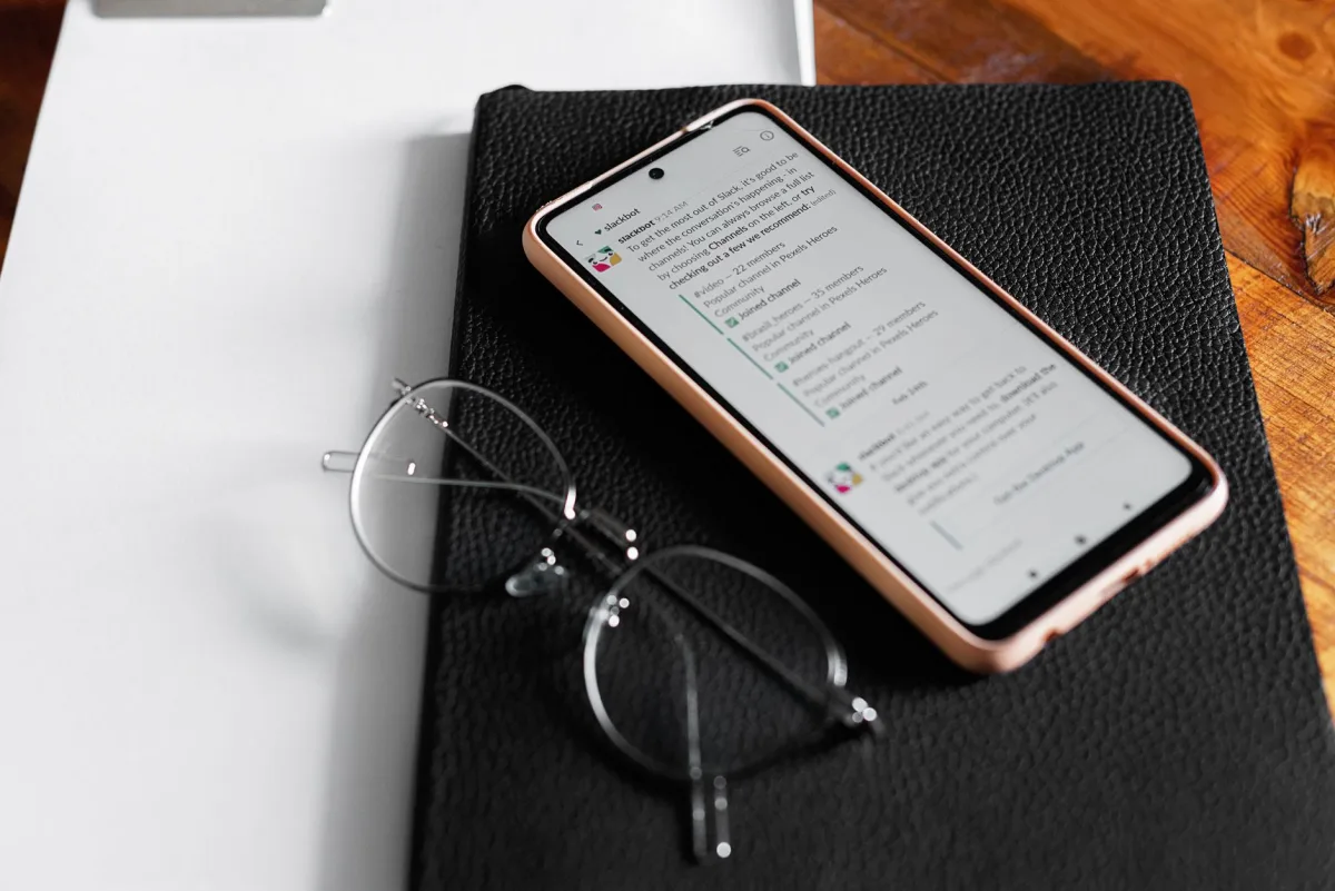 Smartphone displaying chat app on desk with notebook and eyeglasses. Ideal for technology and themes. Smartphone displaying chat app on desk with notebook and eyeglasses. Ideal for technology and themes.